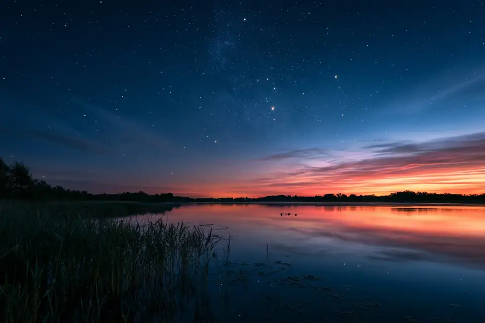 un ciel de nuit rempli d’étoiles au-dessus d’un lac, après le coucher du soleil.
