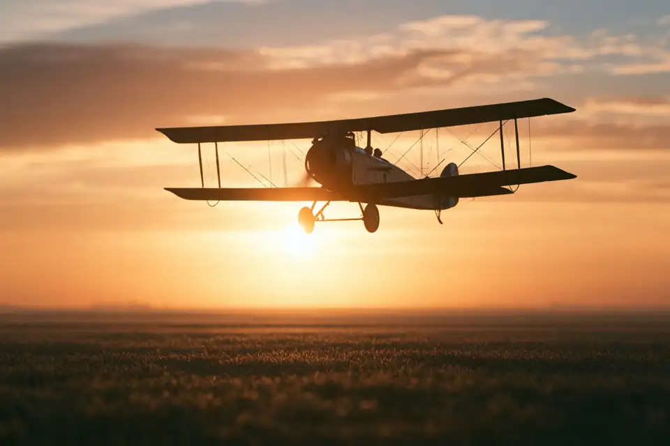 un avion biplan de 1917 décollant d’un champ au petit matin.