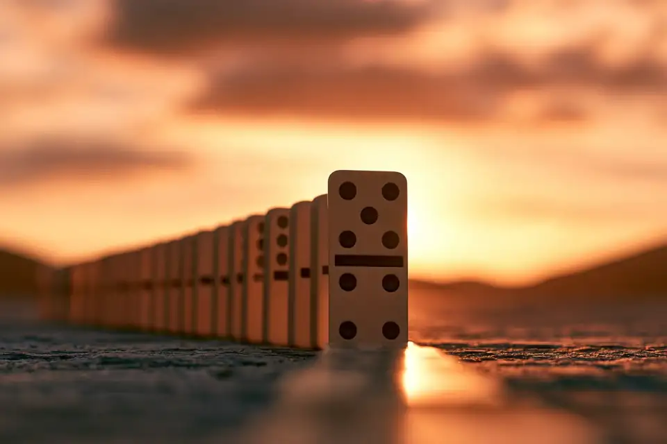 une seule pièce de domino dressée en tête d’une longue rangée qui s’apprête à tomber.