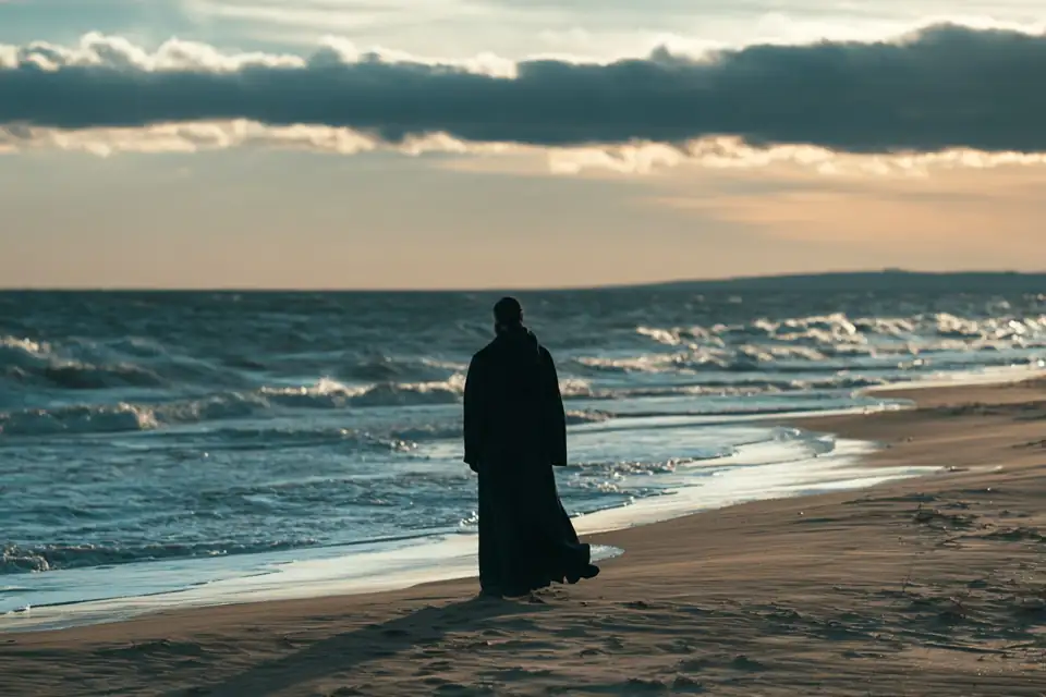 une côte déserte de la mer Noire en hiver, un homme drapé face au vent.