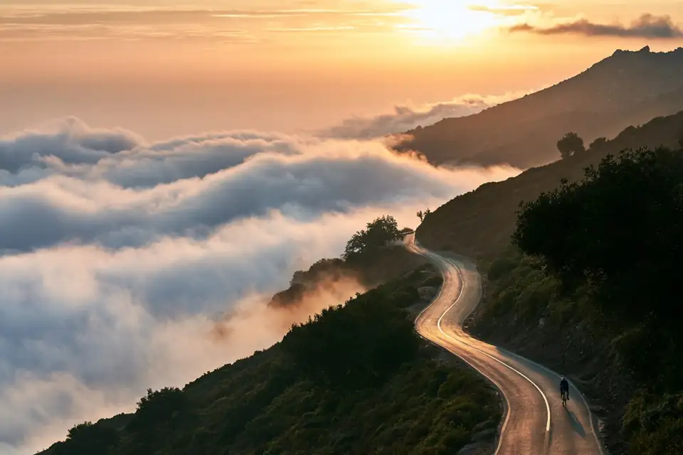 une route de col dans les nuages, un vélo seul dans la pente.