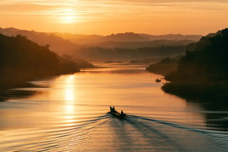 une barque qui suit le courant d’une rivière calme au crépuscule.