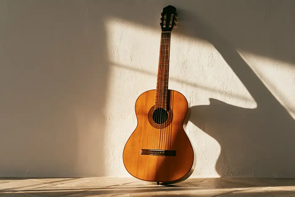 une guitare posée contre un mur blanc de Séville, au soleil couchant.