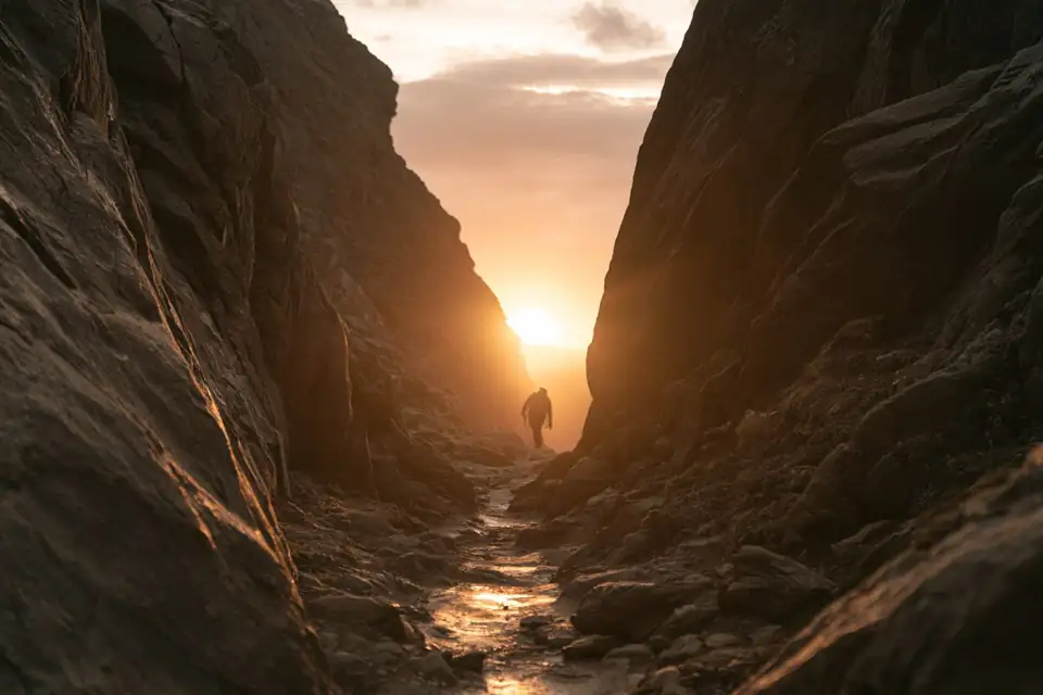 un chemin qui se fraie entre des rochers, une silhouette qui escalade.